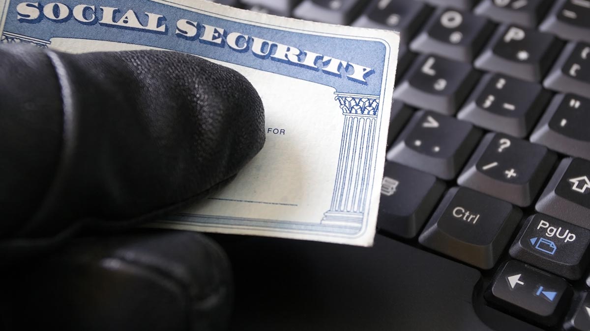 social security card being held by a black gloved hand