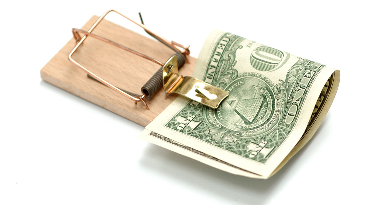 Dollar bill attached to a mouse trap representing a tax trap