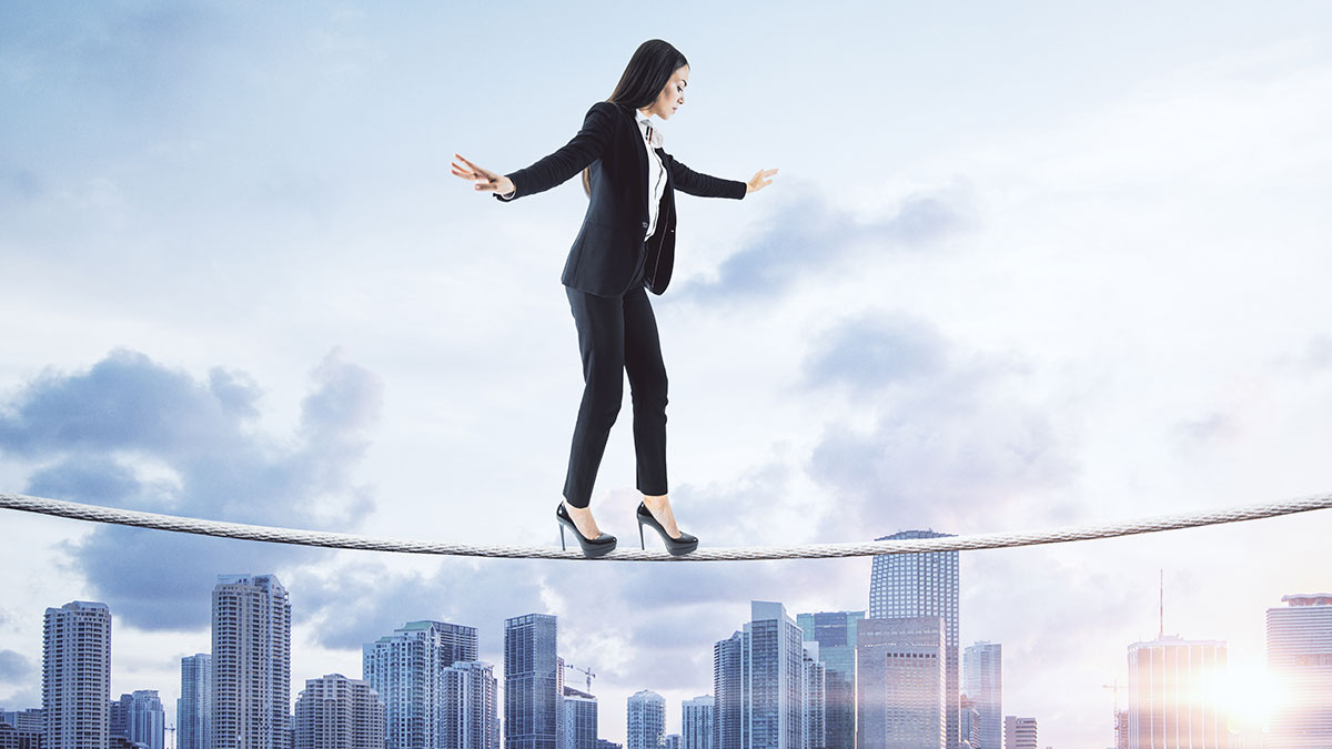 Business Woman walking a tightrope above a cityscape