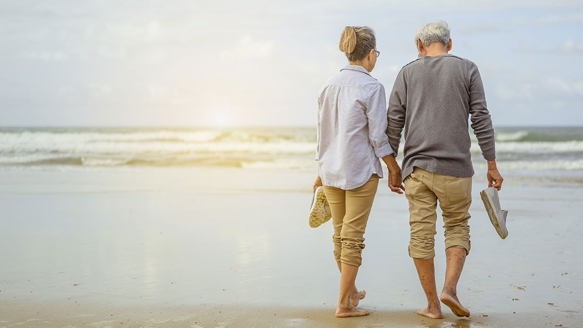 retired couple walking on the beach
