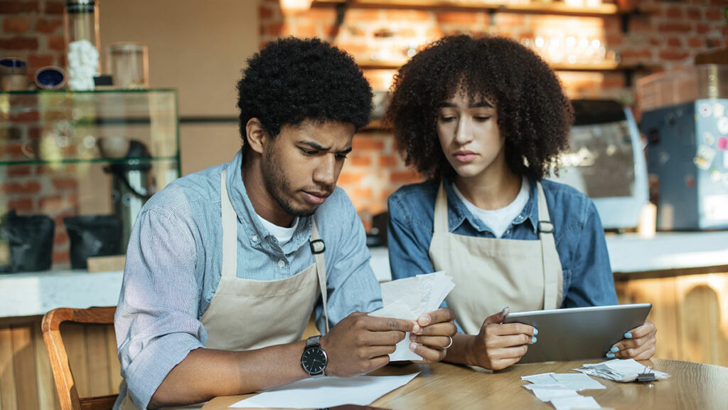 young restauranteur couple looking over paperwork concerned about surprise bills for their small business