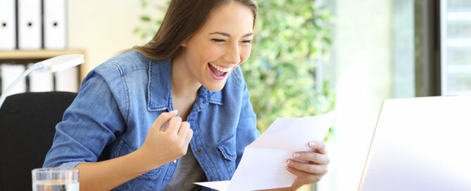 excited woman sitting at a table happy about her tax return