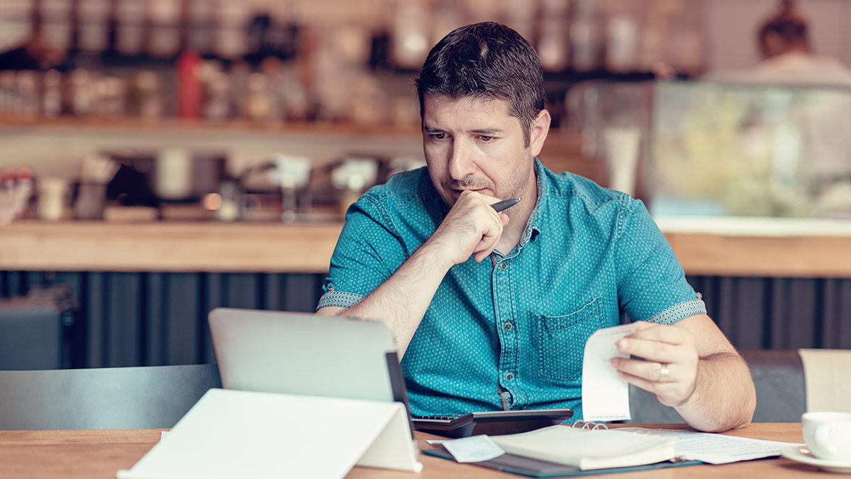 small business owner paying taxes at a table on his laptop