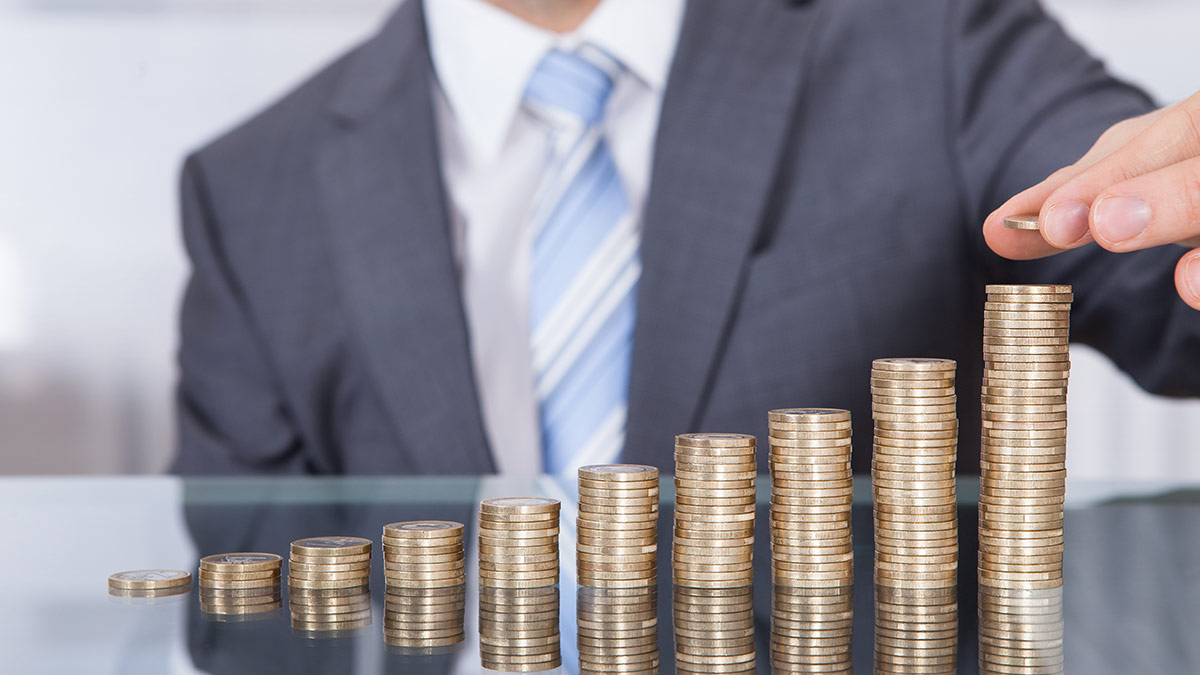 man wearing business suit stacking coins increasing in value