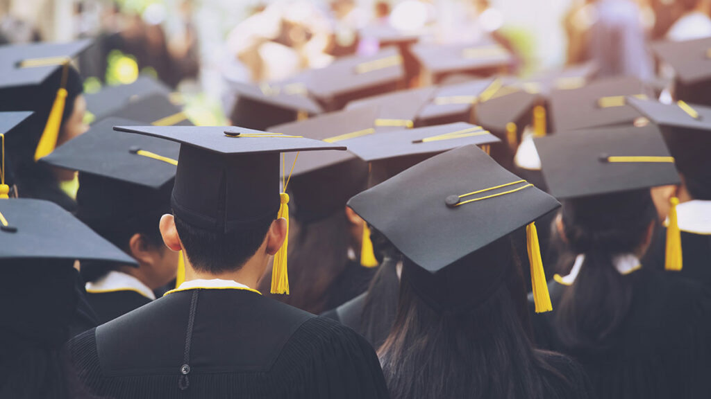 A group of graduates wearing black robes and motarboards with golden tassels