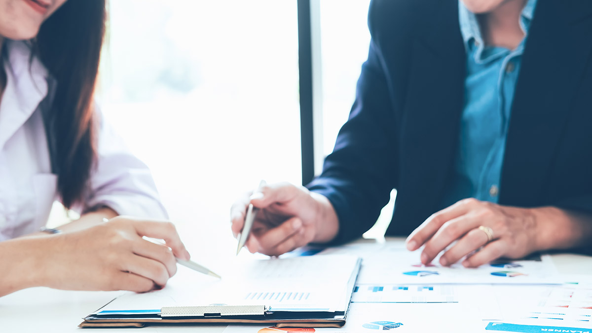 man and woman sitting at a desk looking over papers for a tax review