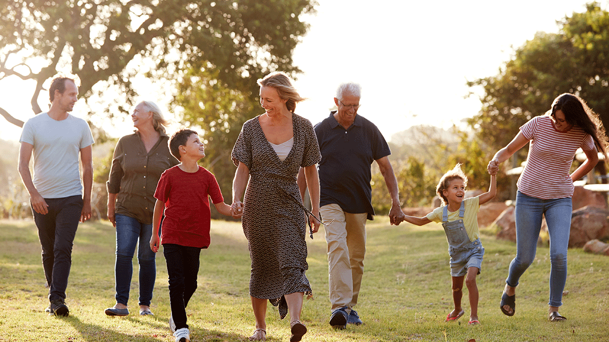 happy grandparents parents children walking through a field